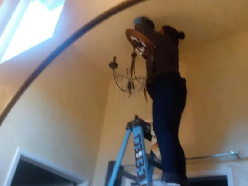 Electrician installing a chandelier in a Home Gardens residence